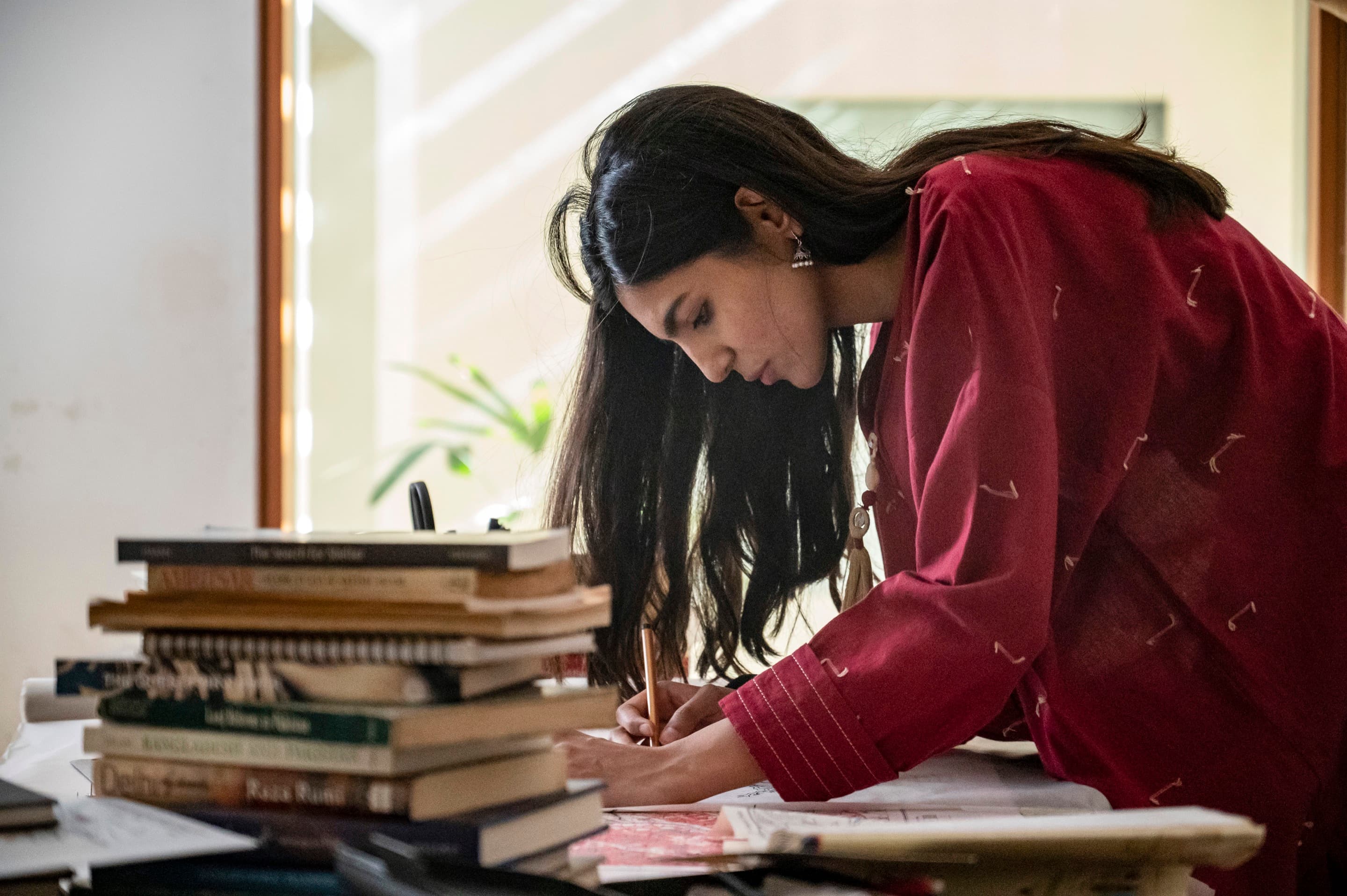 Namra Khalid drawing. A pile of books sit in the foreground.